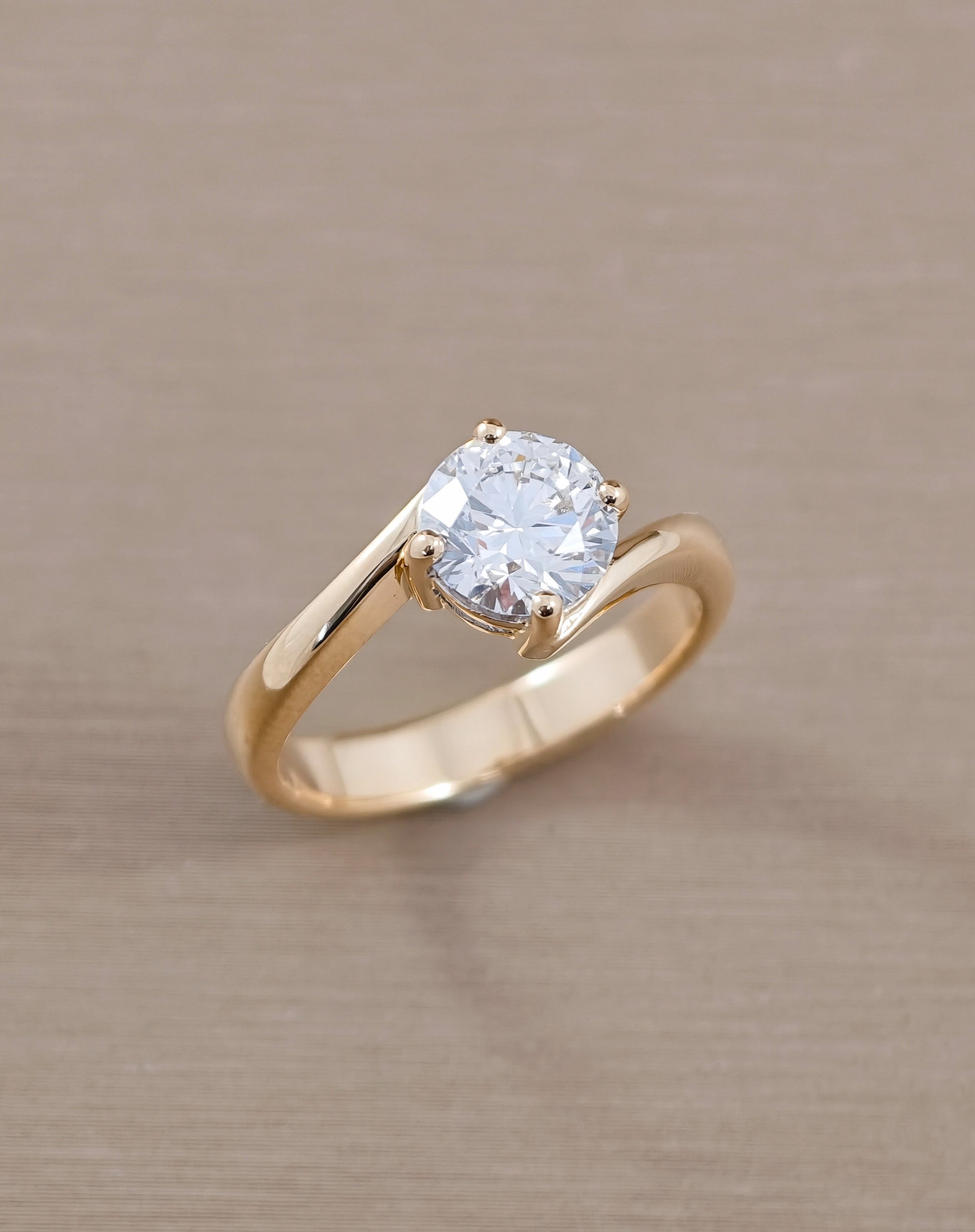 A gold solitaire engagement ring with a round brilliant-cut DIAMOND