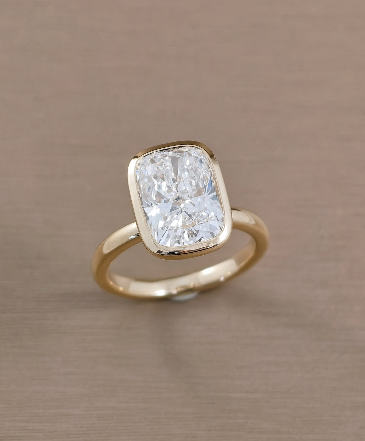 Angled view of cushion bezel set lab grown diamond ring with minimalist design