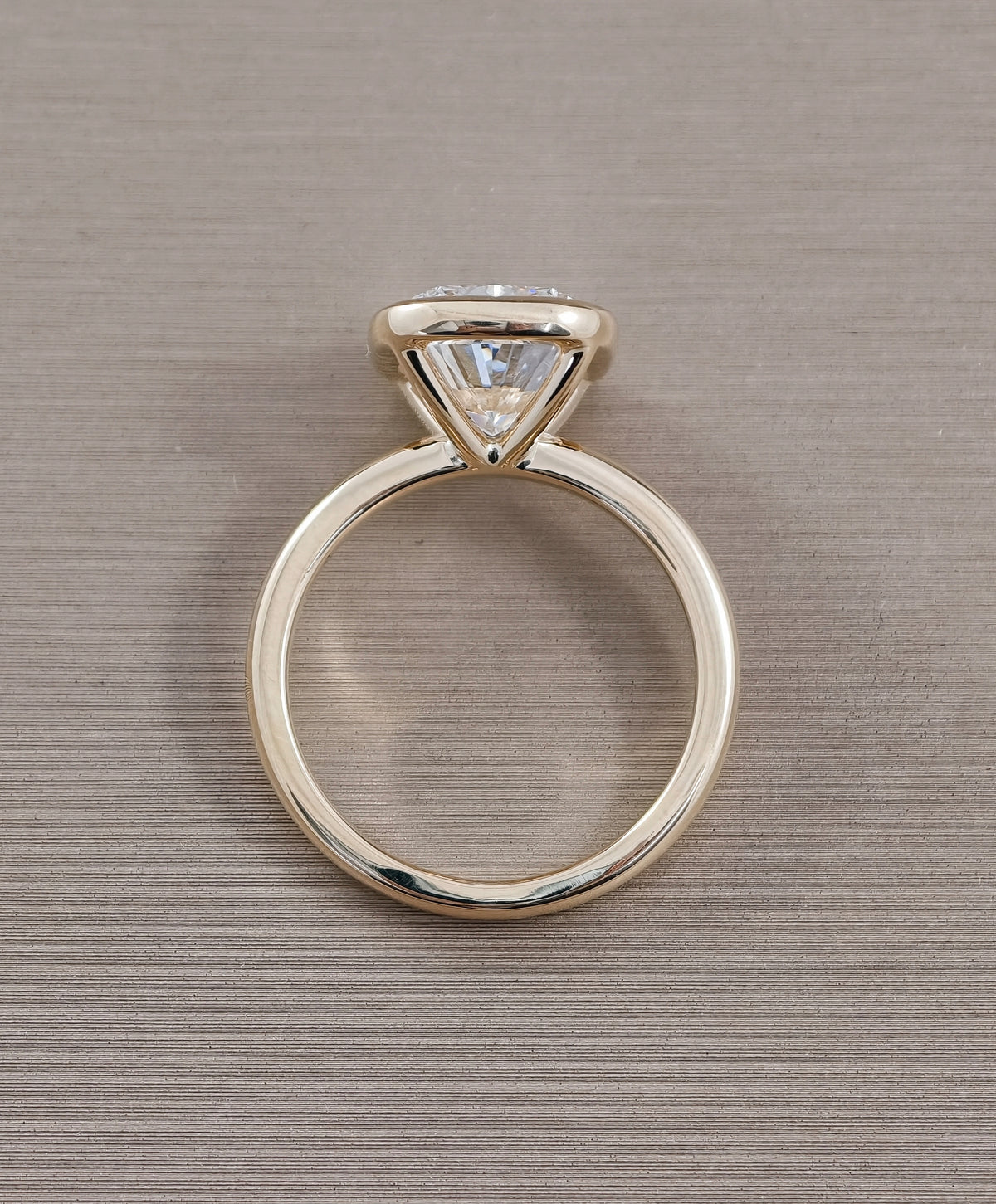 Side view of cushion cut lab grown diamond engagement ring with modern bezel setting