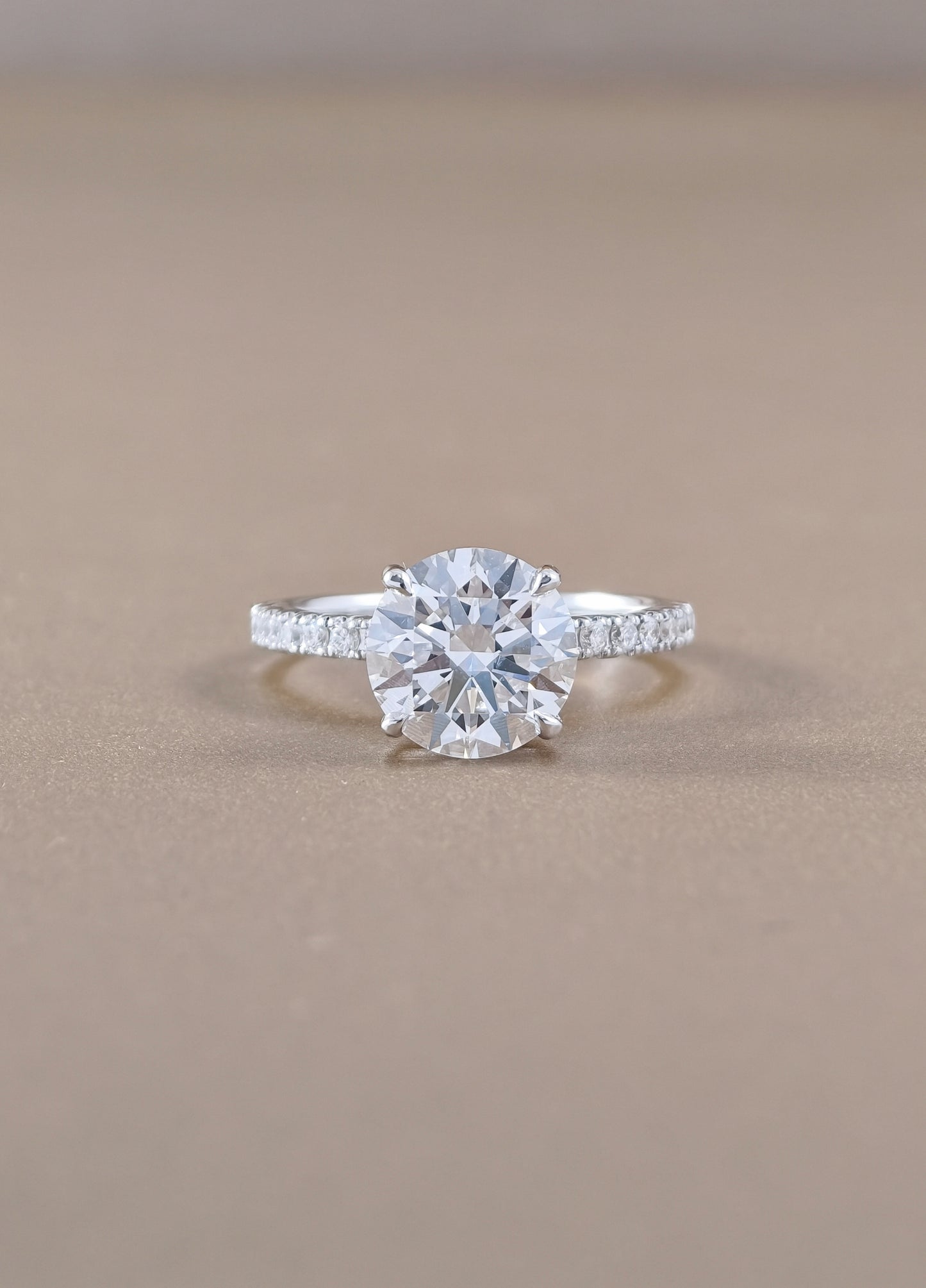 A round-cut diamond engagement ring with a white gold set with small pavé diamonds