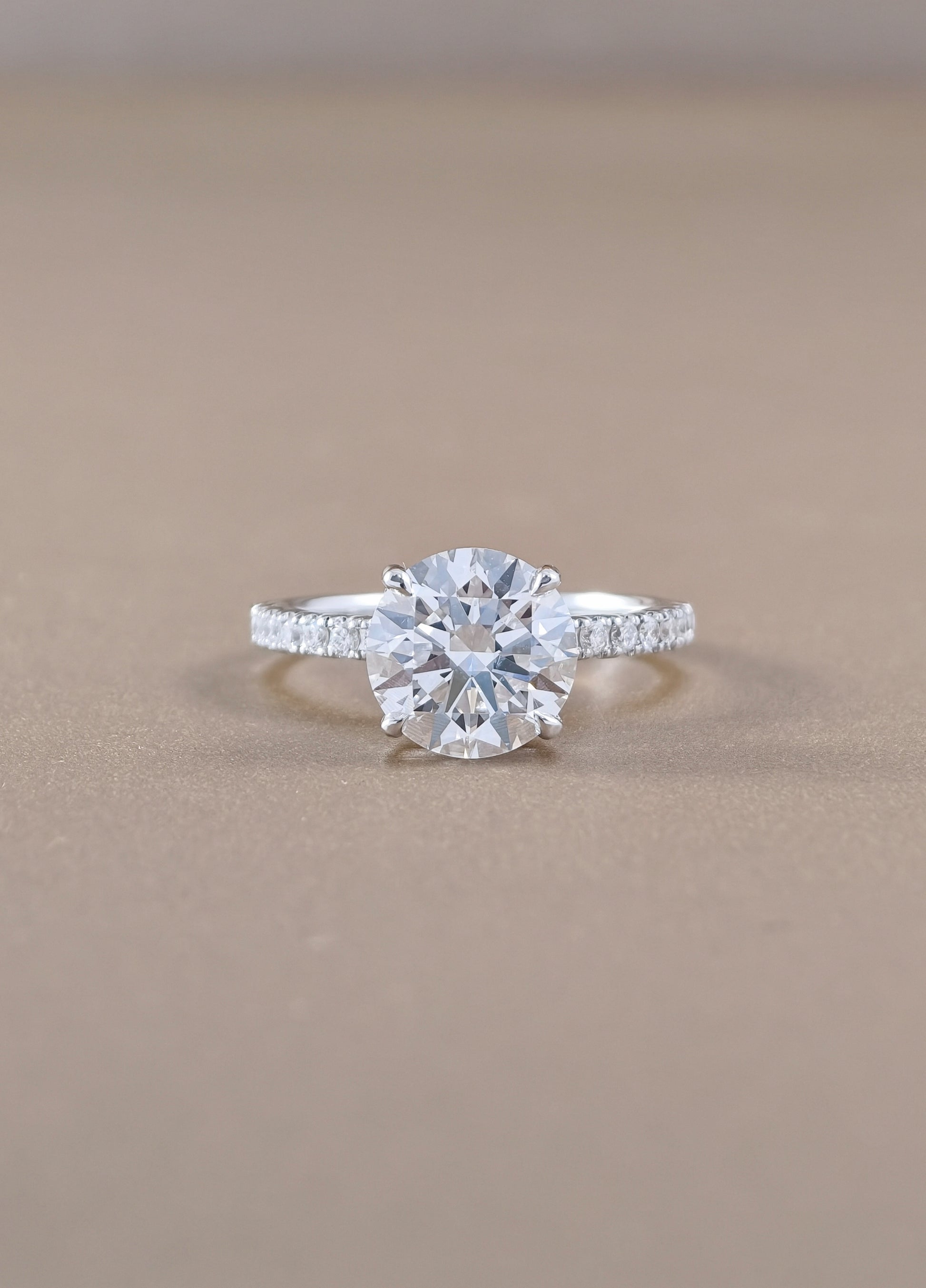 A round-cut diamond engagement ring with a white gold set with small pavé diamonds