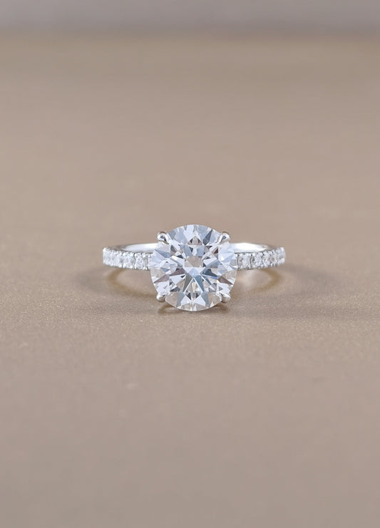 A round-cut diamond engagement ring with a white gold set with small pavé diamonds