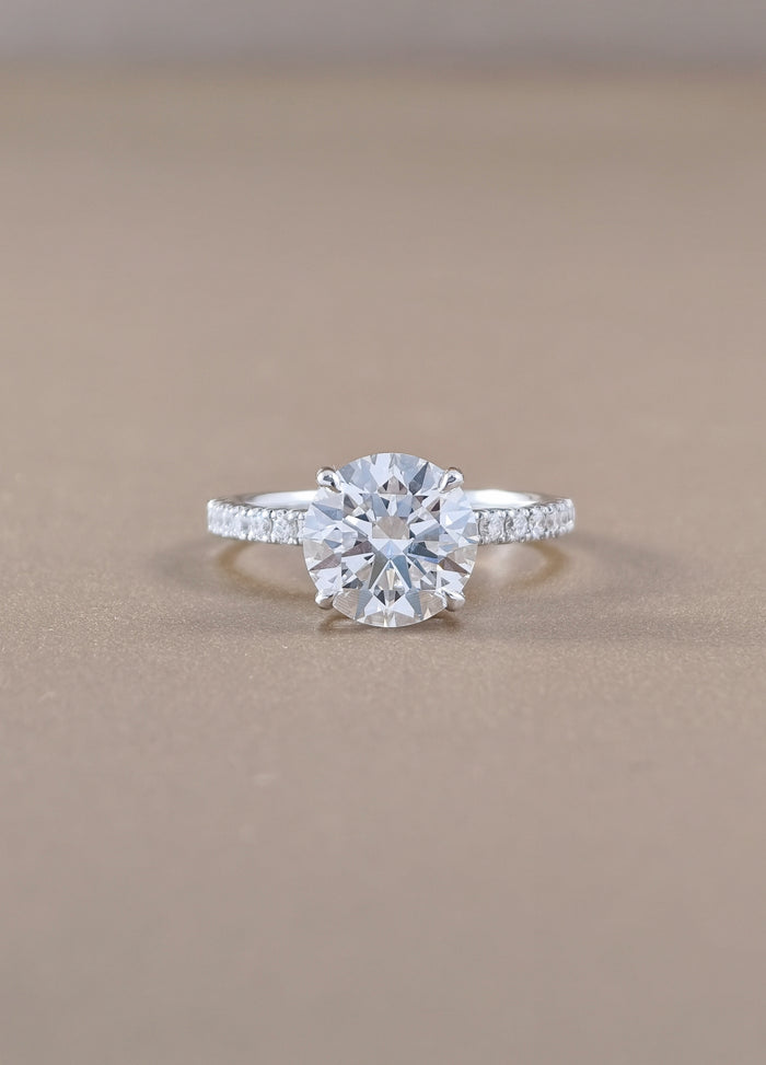 A round-cut diamond engagement ring with a white gold set with small pavé diamonds