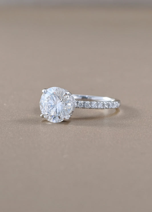 A round-cut solitaire engagement ring with a pavé band