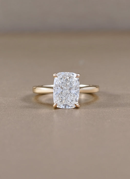 A yellow gold ring with a cushion-cut diamond lab grown set in a four-prong setting, 