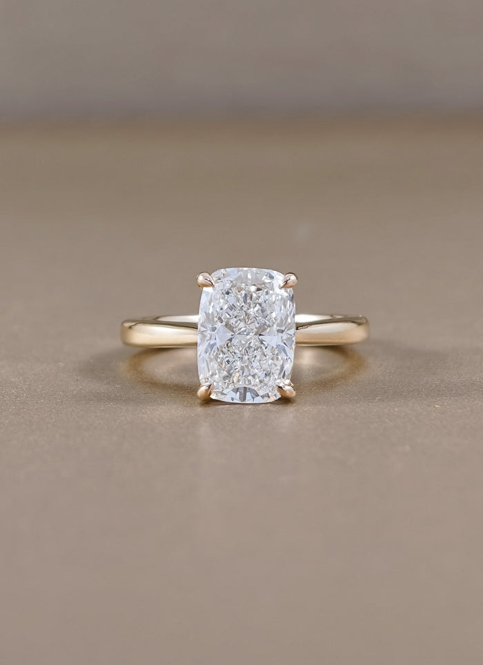 A yellow gold ring with a cushion-cut diamond lab grown set in a four-prong setting, 