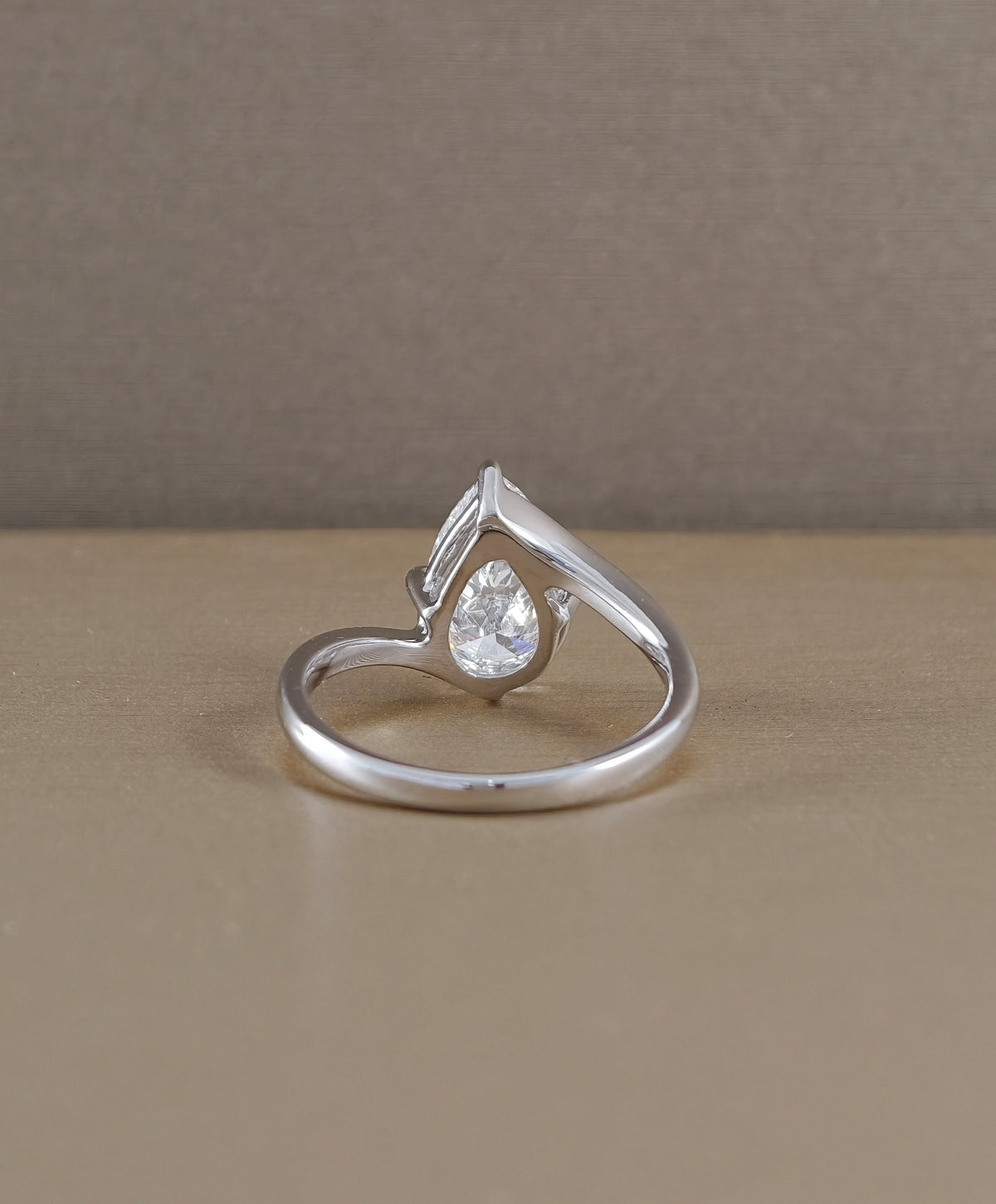 Rear view of pear cut diamond curved solitaire engagement ring showing white gold setting structure