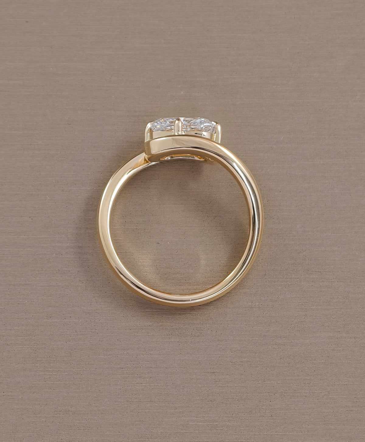 Side view of cushion cut lab grown diamond solitaire ring with sculptural yellow gold twist setting