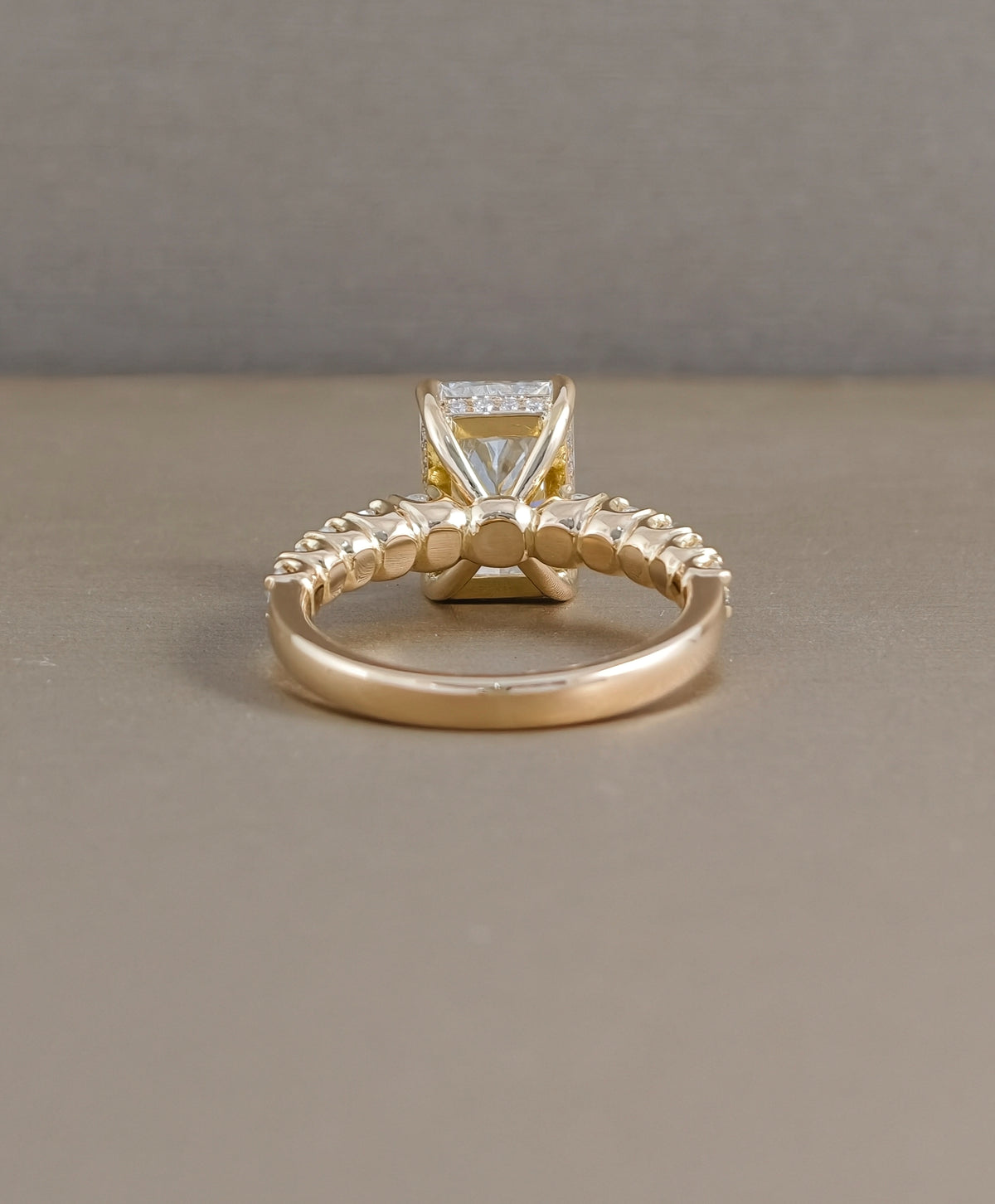 Rear view of radiant cut lab grown diamond engagement ring with yellow gold setting and diamond accented band