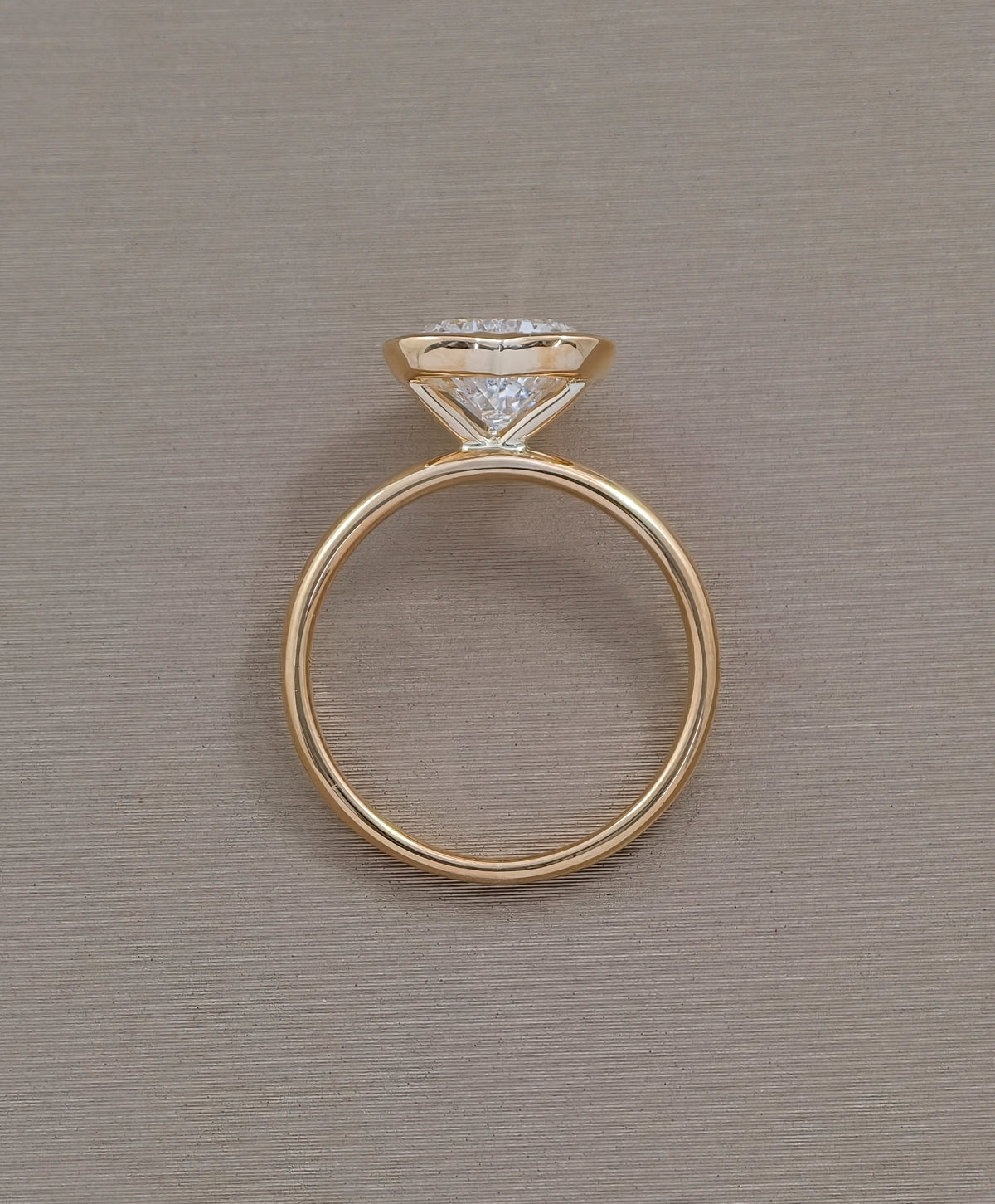 Side profile of heart shaped lab grown diamond engagement ring with smooth yellow gold bezel and polished band