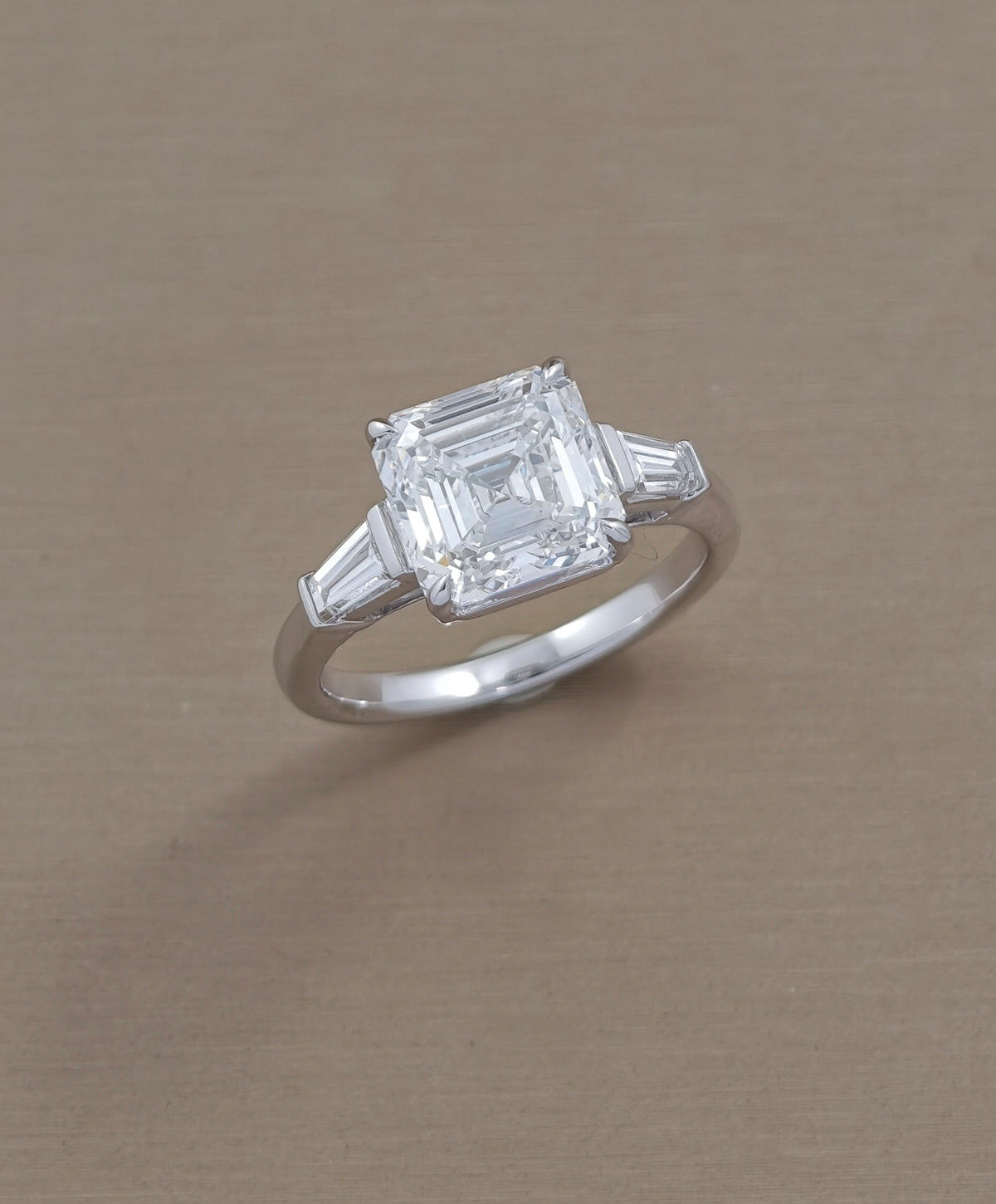 Angled view of Asscher cut lab grown diamond engagement ring with two side diamonds in white gold