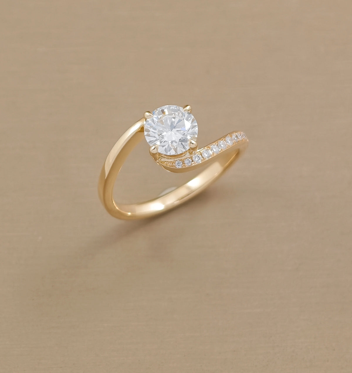 Angled top view of round lab grown diamond engagement ring with flowing yellow gold twist band