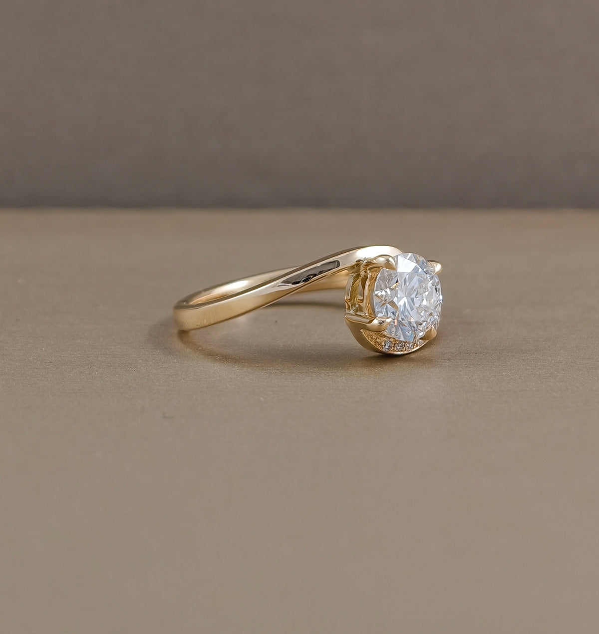 Side angle of Sunset Wave round lab grown diamond ring showing asymmetrical twist band in yellow gold