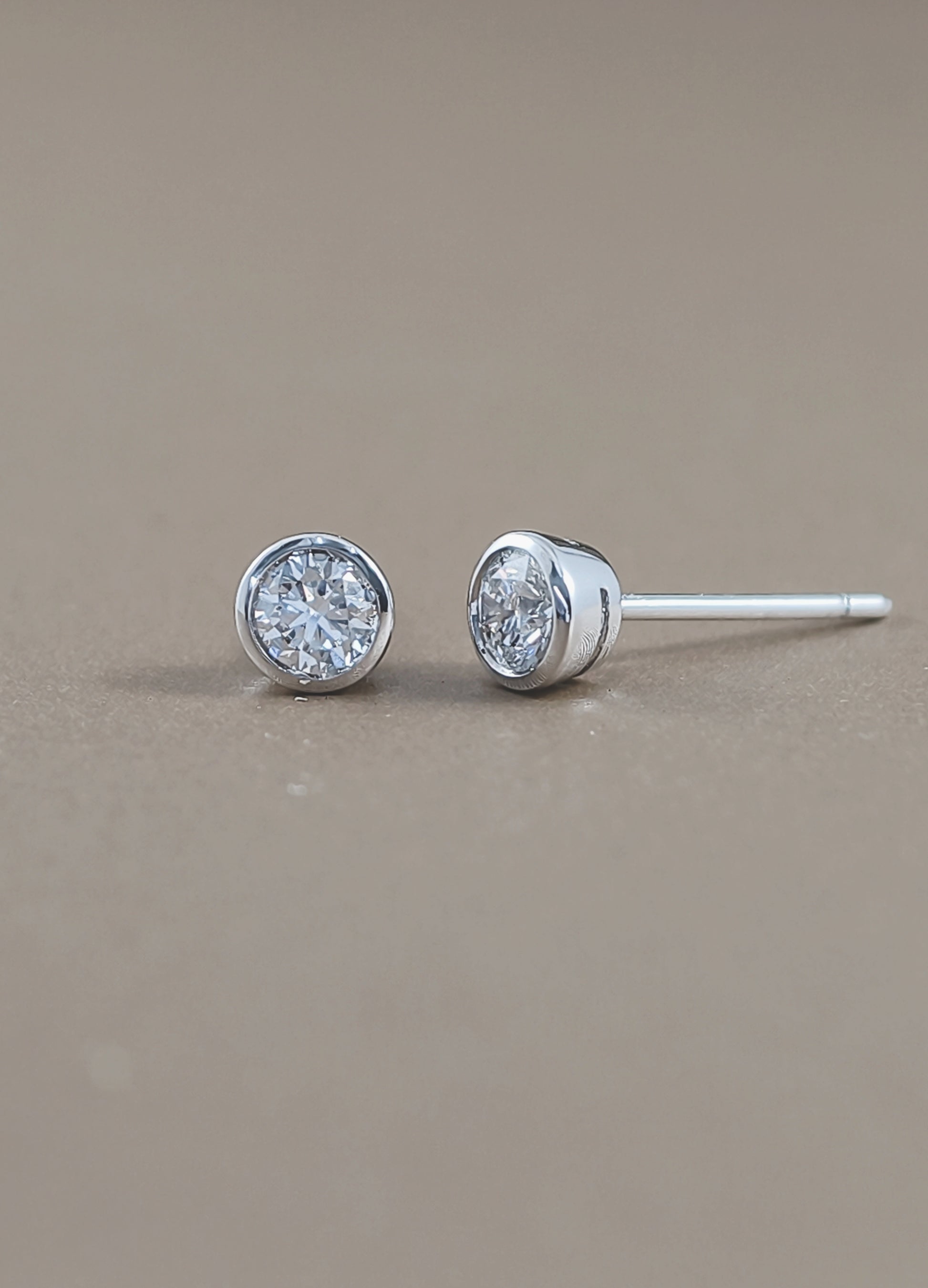 A pair of round bezel-set lab grown diamond earring in white gold setting