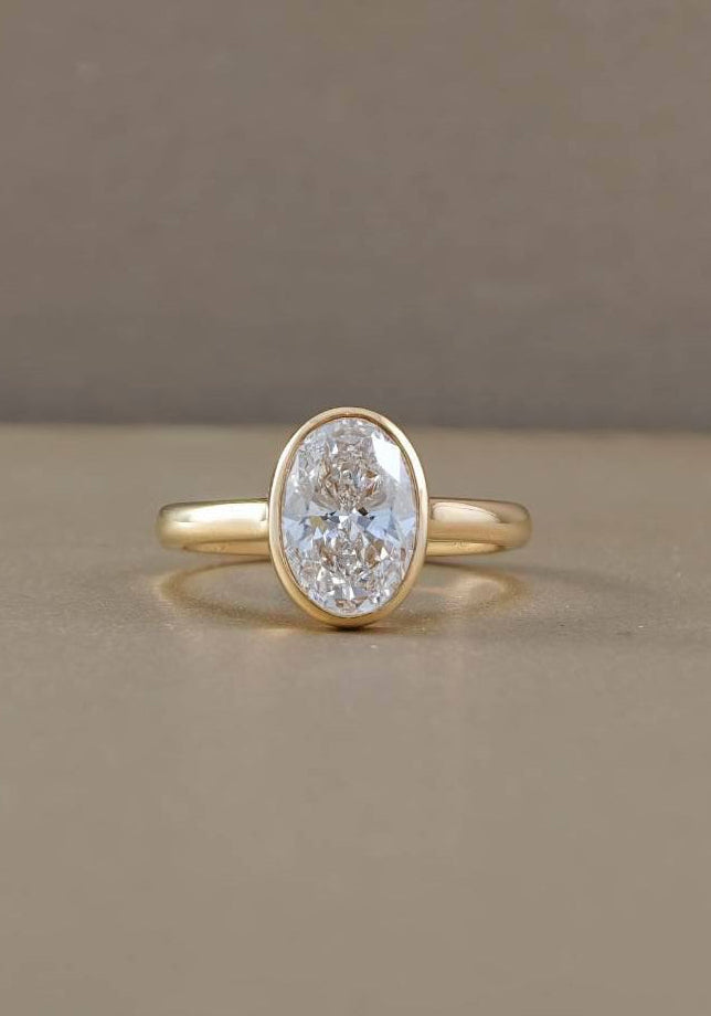 Oval bezel set lab grown diamond engagement ring in yellow gold, front view showing oval solitaire diamond by Sphere Diamond