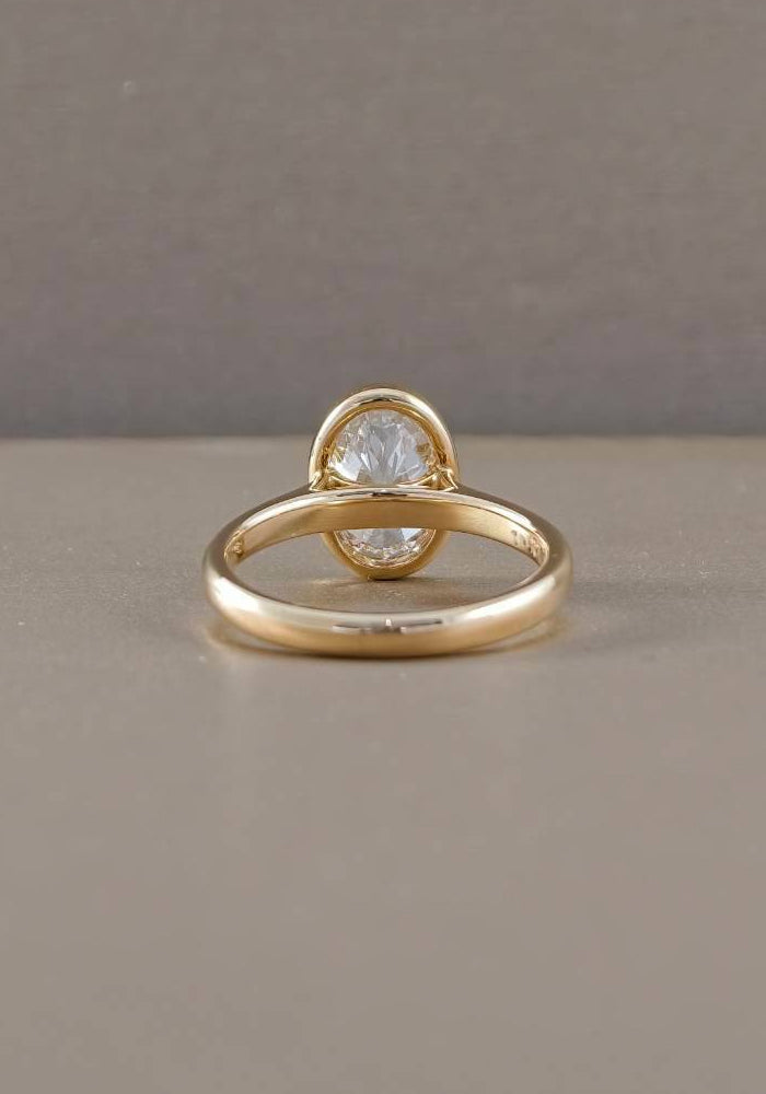Rear angle of yellow gold oval bezel lab grown diamond solitaire engagement ring showing polished ring band
