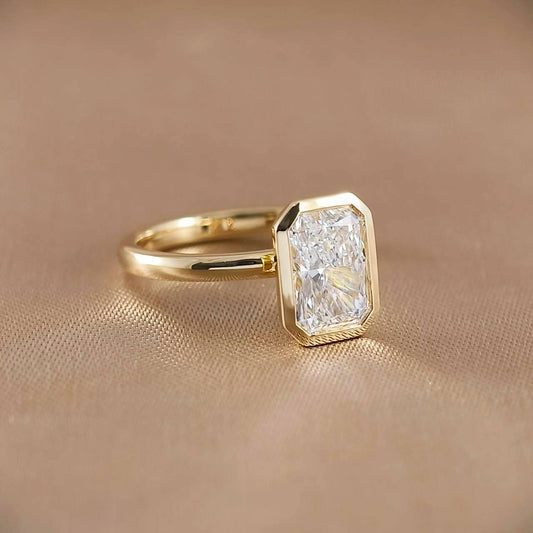 Three-quarter view of Radiant lab grown diamond bezel engagement ring in 18K yellow gold