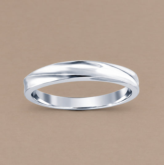 A polished white gold band ring with a wavy, fluid organic curve, displayed on a solid warm beige background.